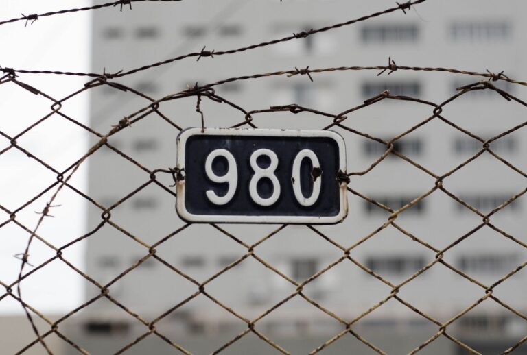 Close-up of a barbed wire fence with a metal number plate. Symbolizes security and restriction.