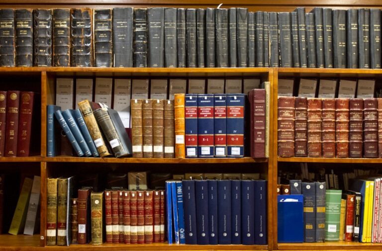 Uma Estante Cheia De Livros Em Cima De Prateleiras De Madeira h_YX8re2Uu4