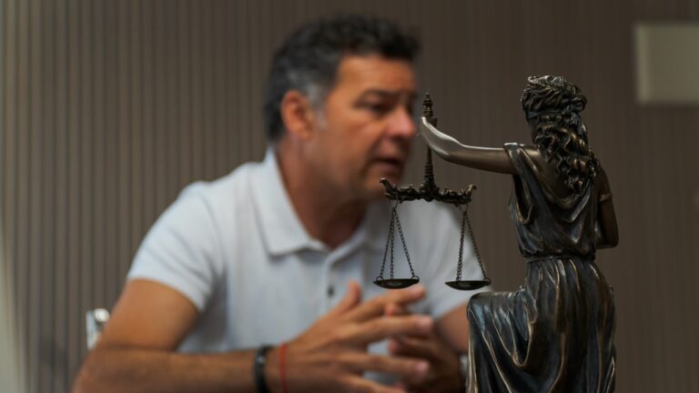 Um Homem Sentado Em Uma Mesa Em Frente a Uma Estatua EoPb1QSkpvQ