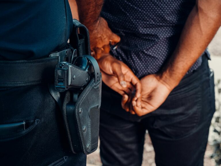 Close-up of a police officer arresting a suspect with visible firearm outdoors.